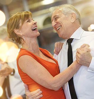 Ältere Dame und älterer Mann tanzen glücklich